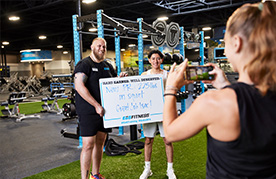 eos gym member side by side with personal trainer holding up white board indicating how much they lifted